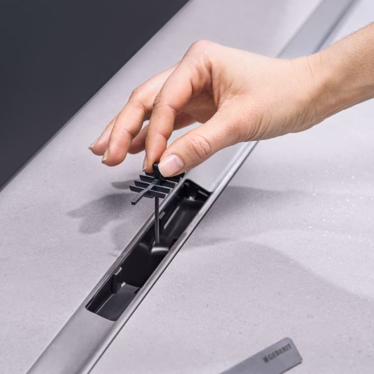 Hånd som plasserer en hårsil i avløpet Hånd som plasserer en hårsil i avløpet